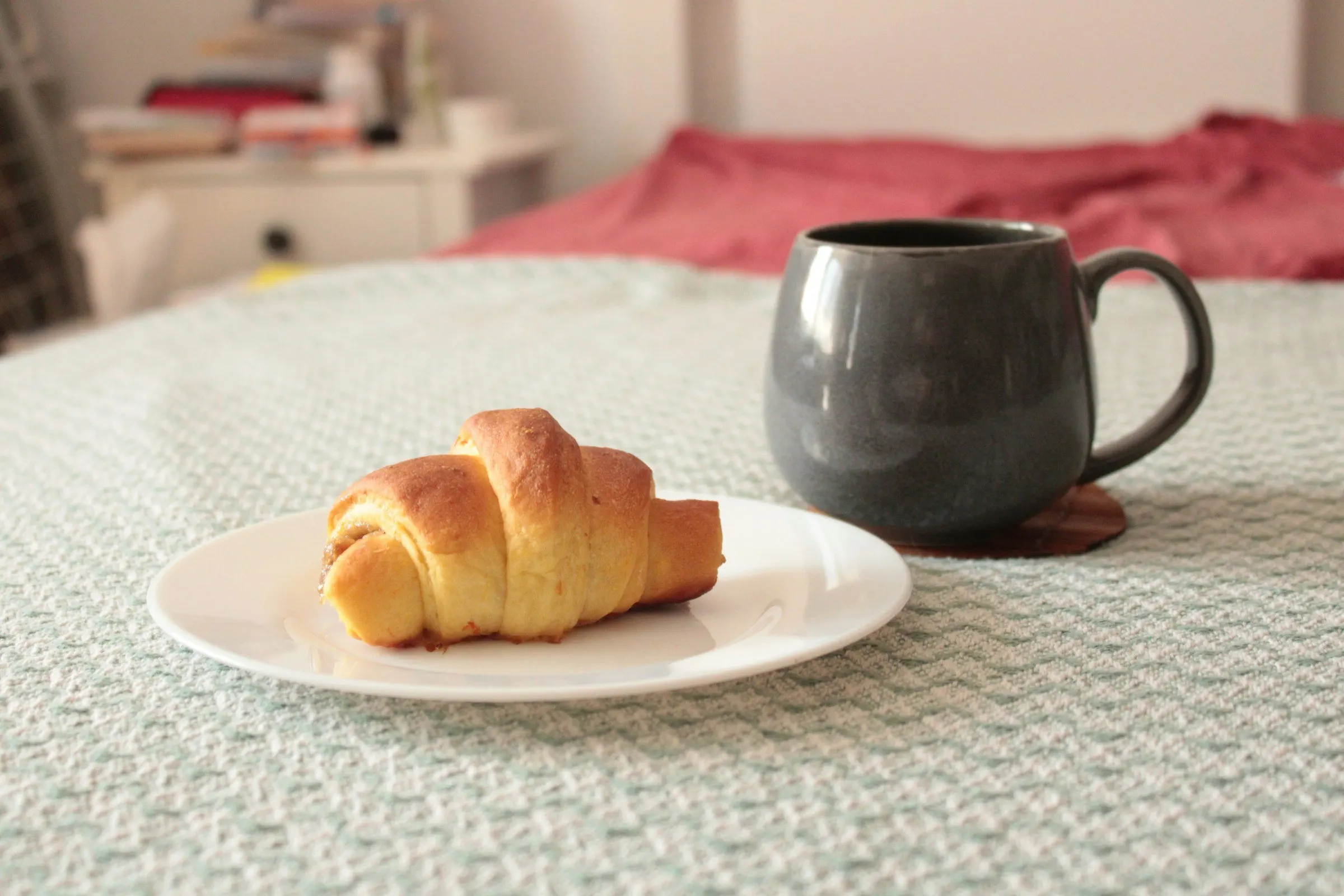 Colazione in camera con croissant e tazza di caffè su un letto