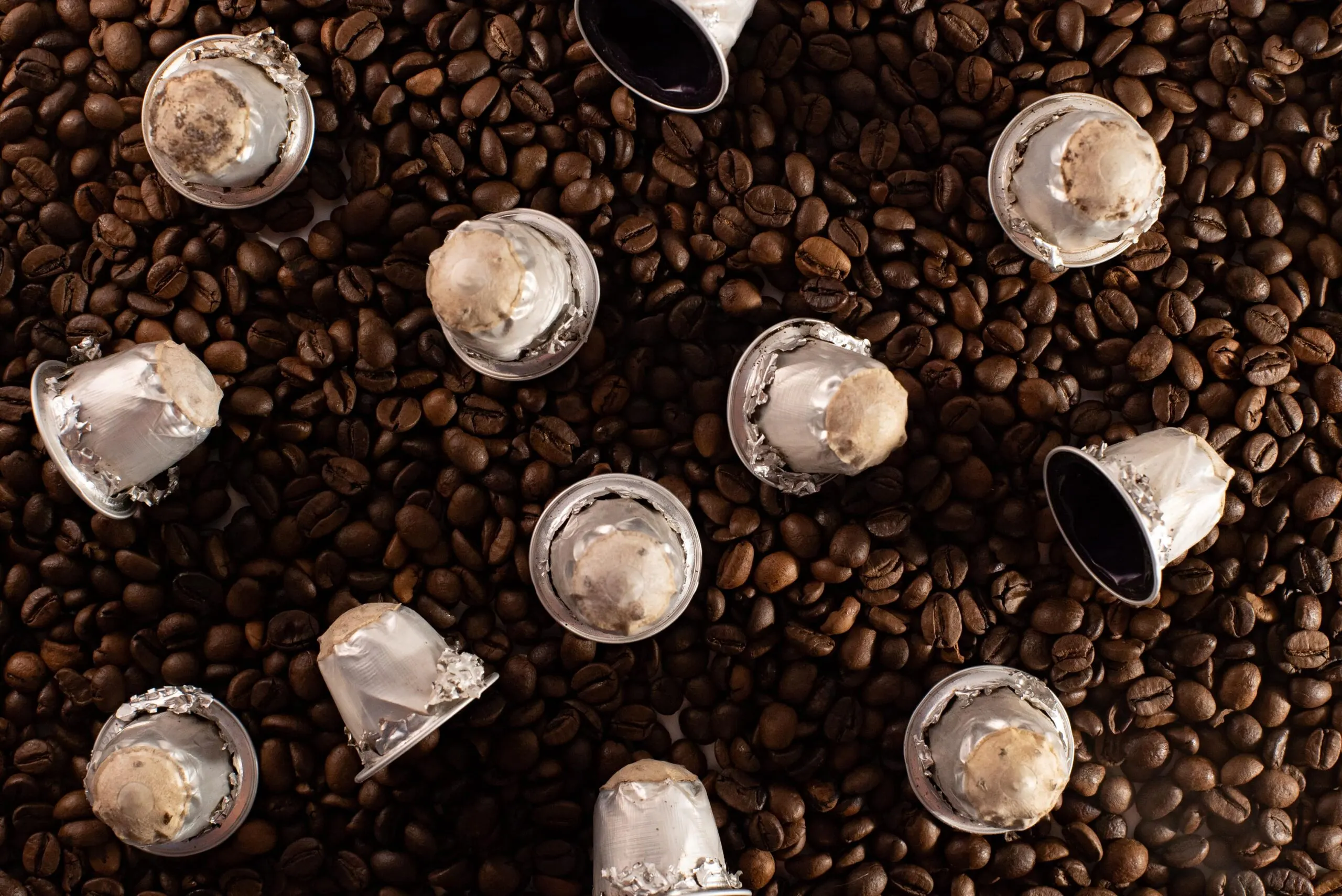 Capsule Nespresso in alluminio usate sparse su chicchi di caffè