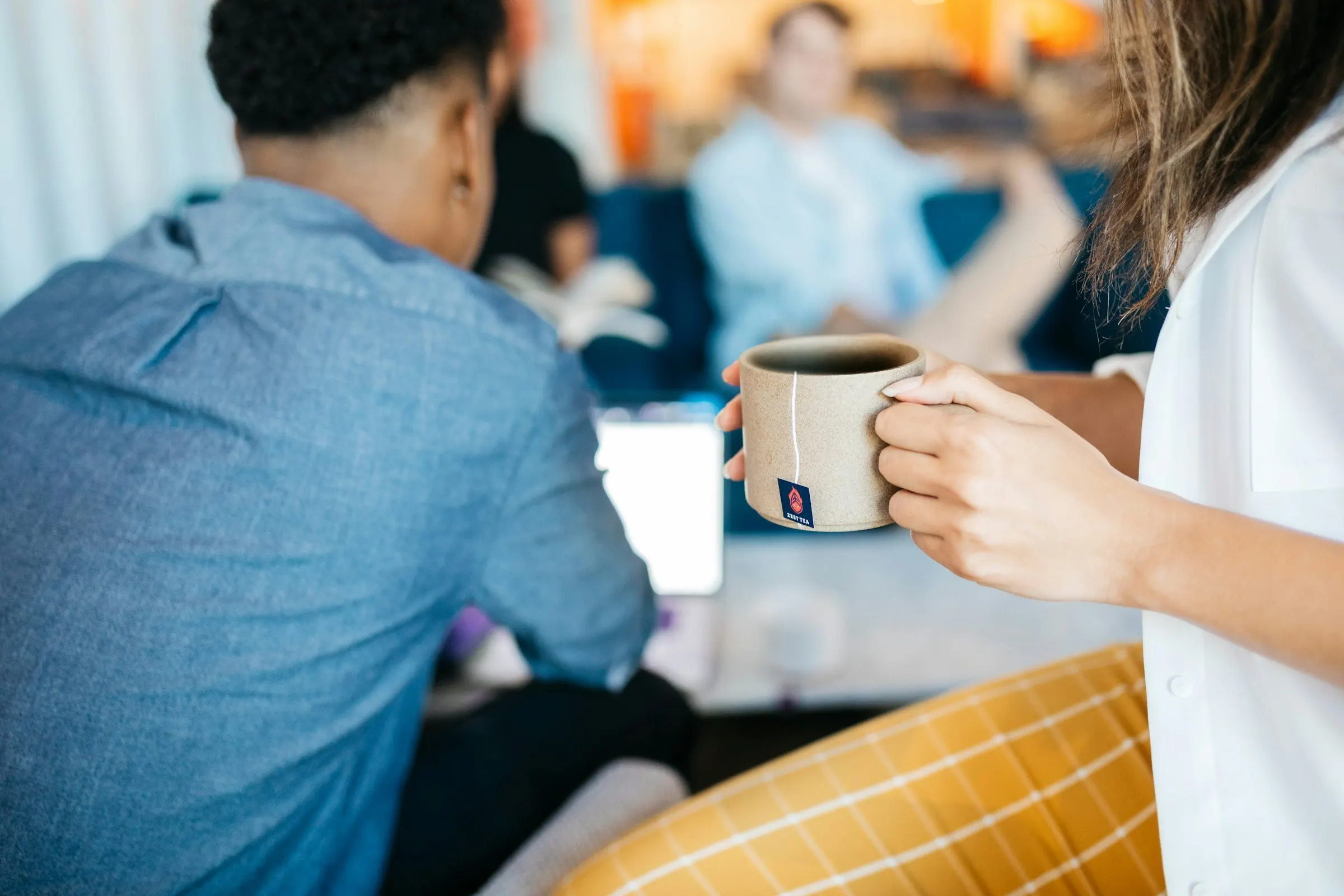 Colleghi durante una pausa caffè in un ufficio condiviso, con una tazza in mano