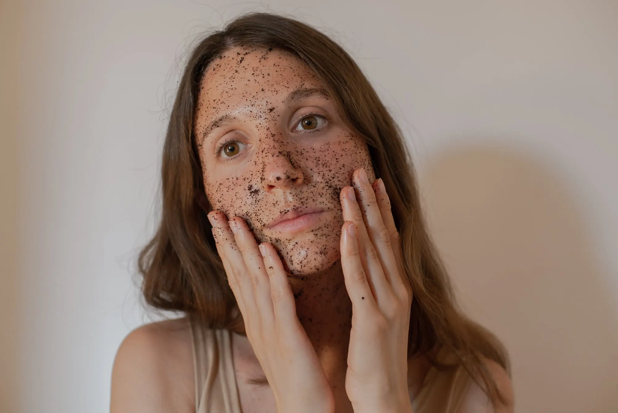 A young woman with a coffee ground mask on her face